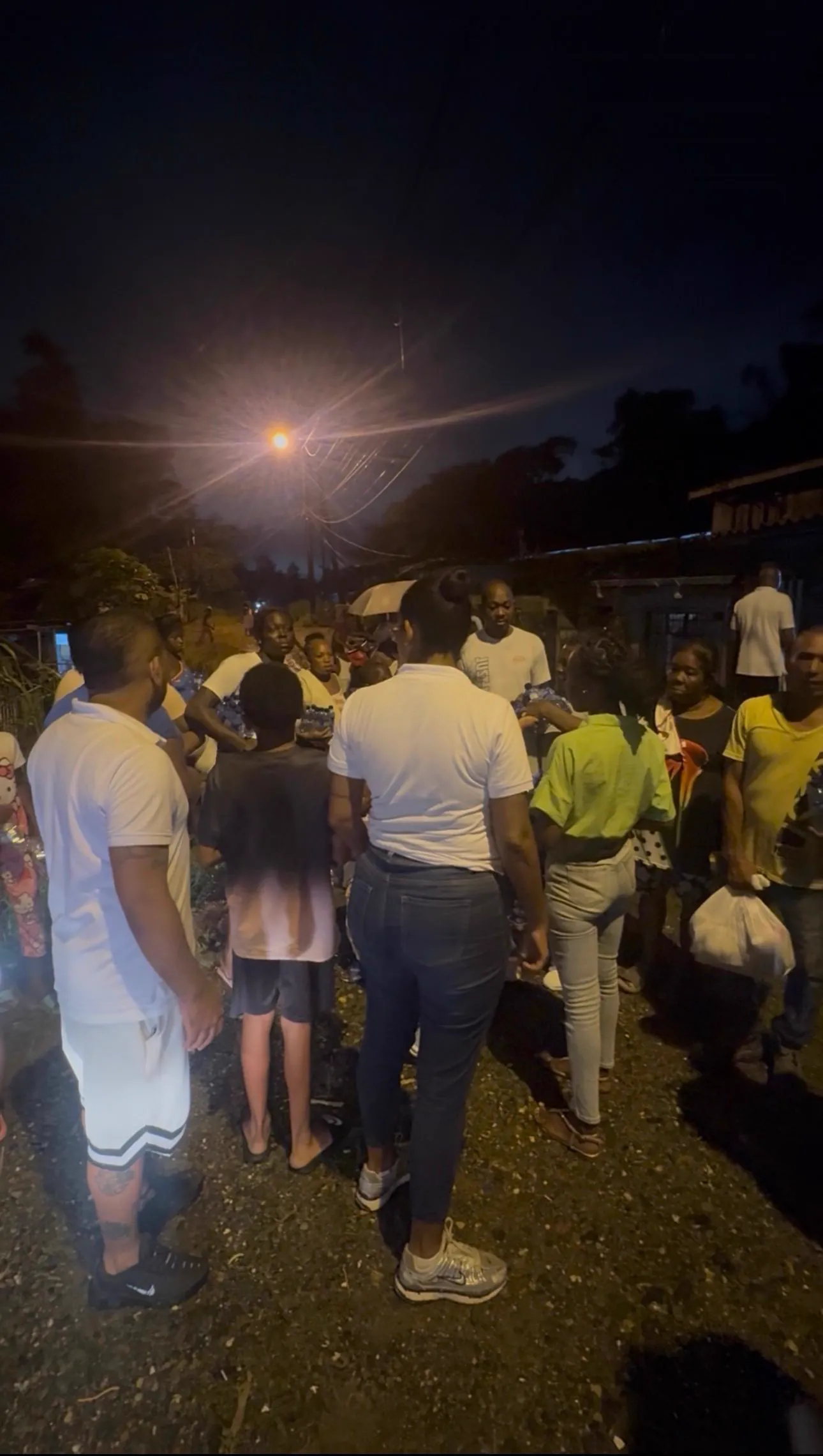 Decenas de habitantes del barrio reunidos de noche en la calle durante la jornada de entrega de ayuda