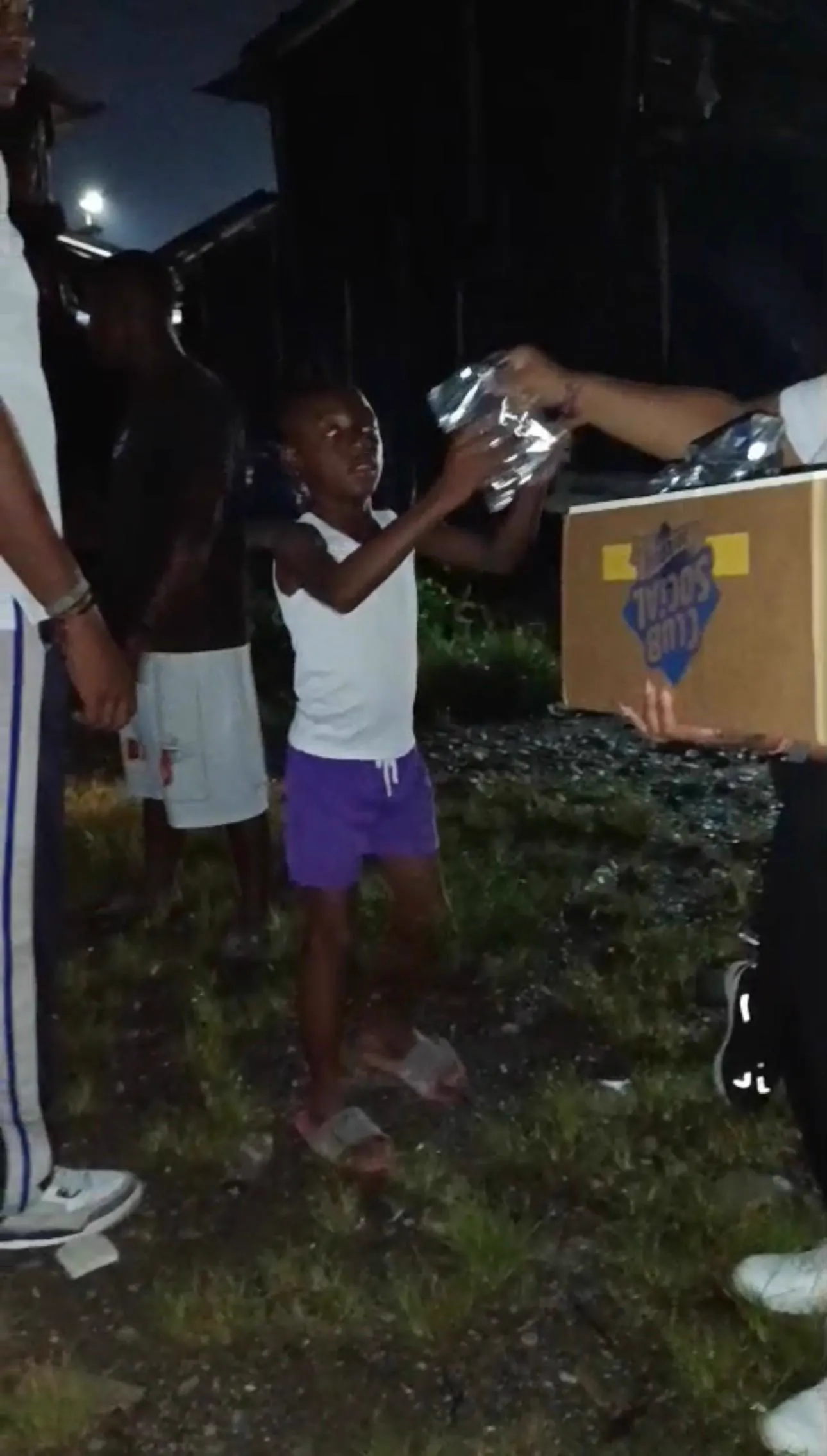 Un joven recibe una caja con ayuda humanitaria de manos de un voluntario durante la jornada nocturna