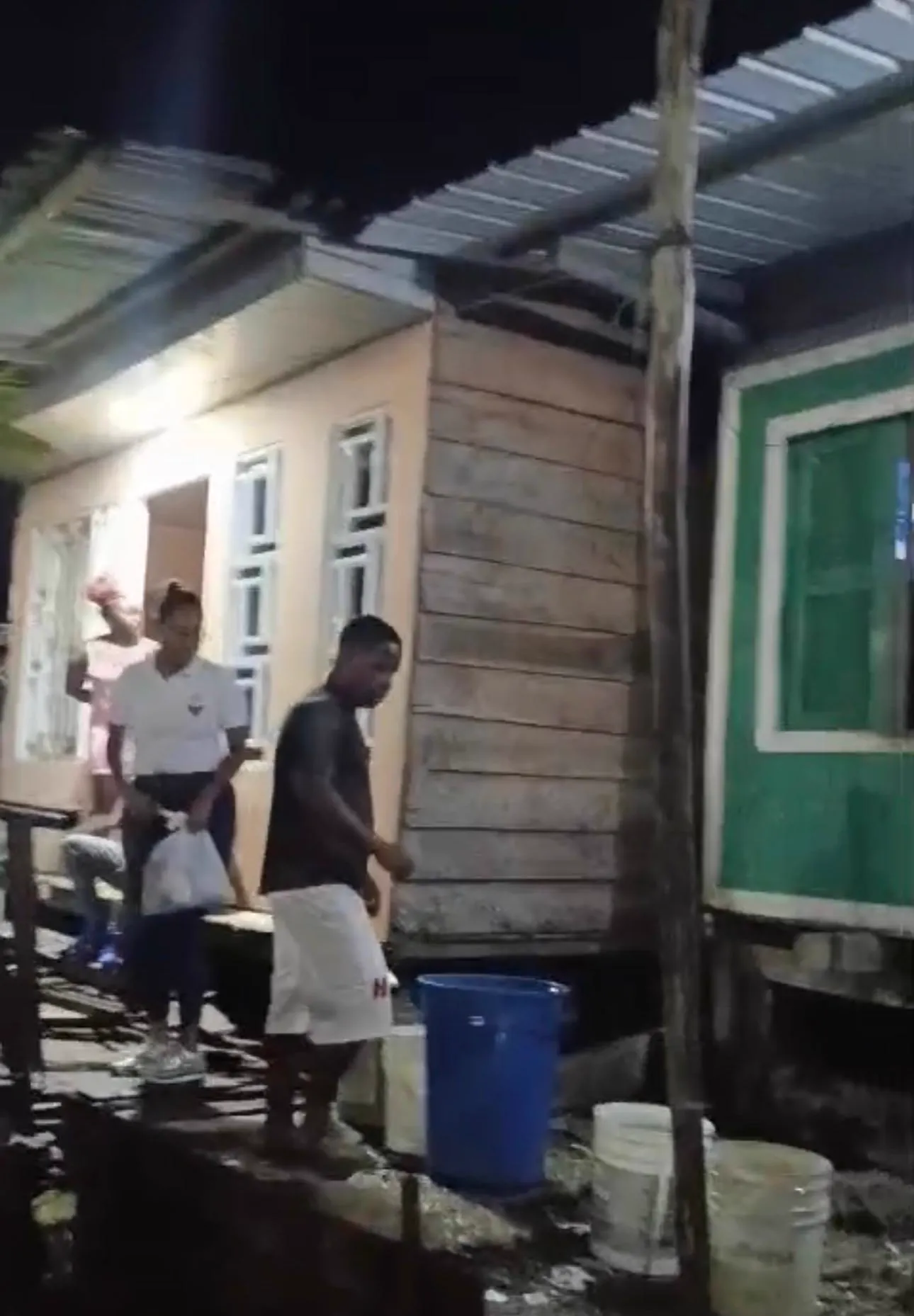 Voluntarios de Luz de Gracia recorren un barrio de casas de madera repartiendo agua y ayuda humanitaria