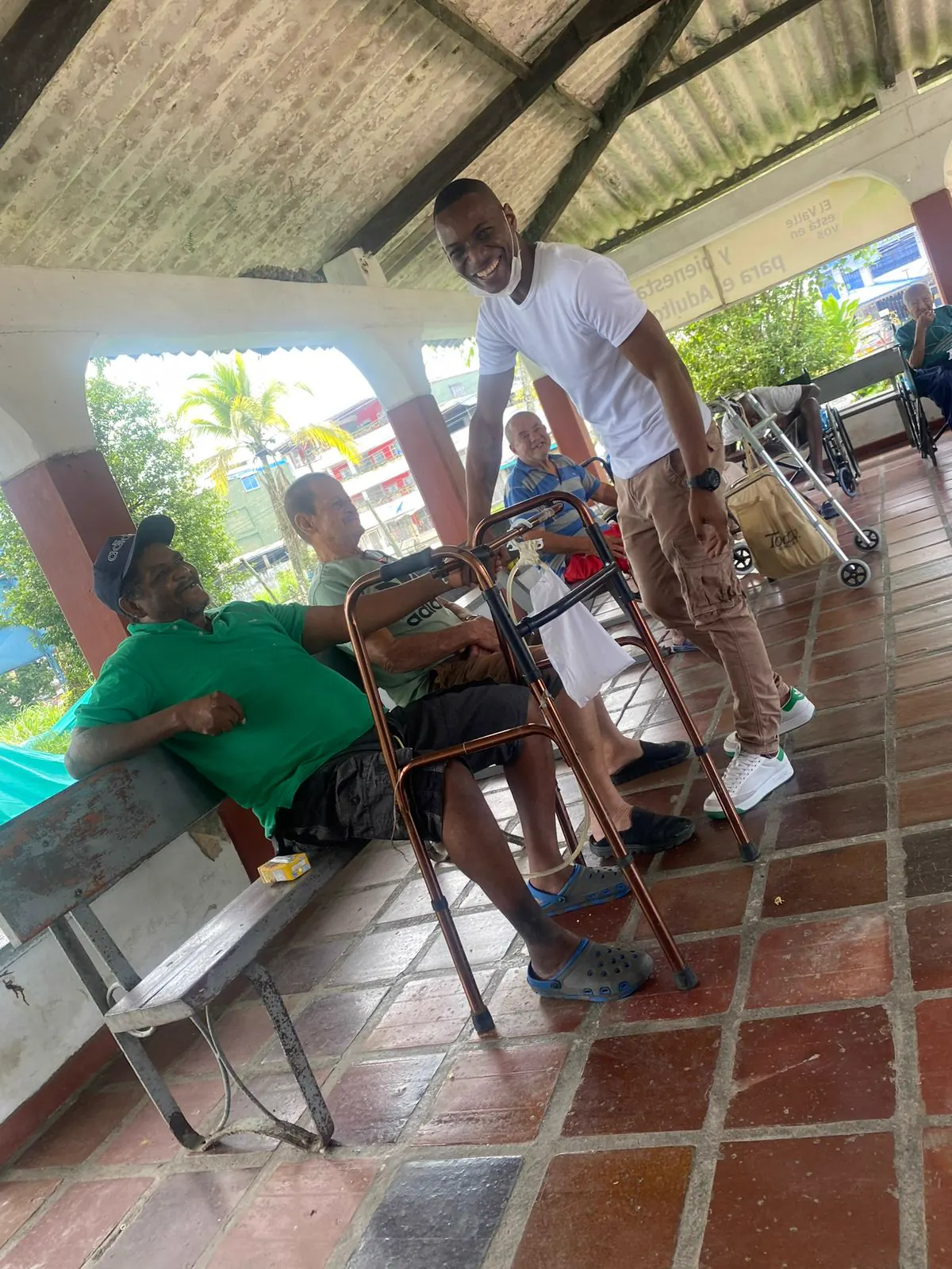Adultos mayores sentados conversando con voluntarios en el patio de un centro de bienestar