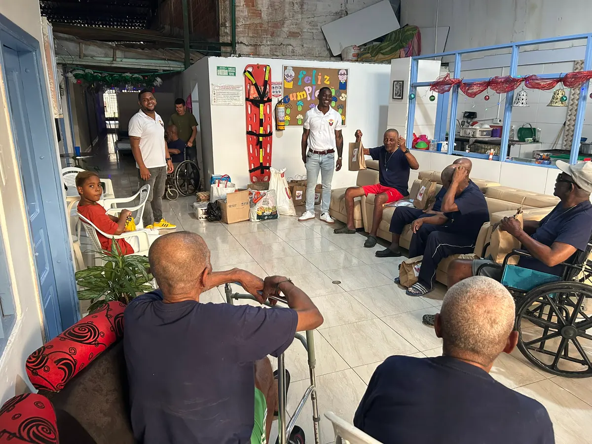 Un voluntario de Luz de Gracia conversa con un grupo de adultos mayores sentados en un centro geriátrico de Buenaventura