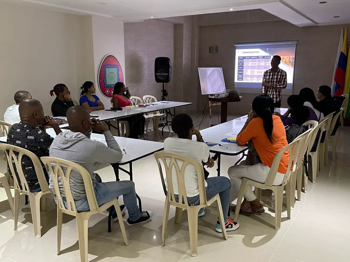 Participantes de un taller de formación ciudadana sentados alrededor de mesas en un salón
